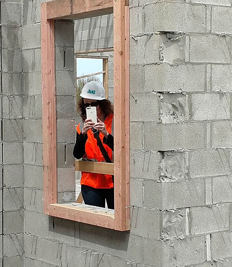 An photo of Megan Scott on a project jobsite holding a camera for the camera. 